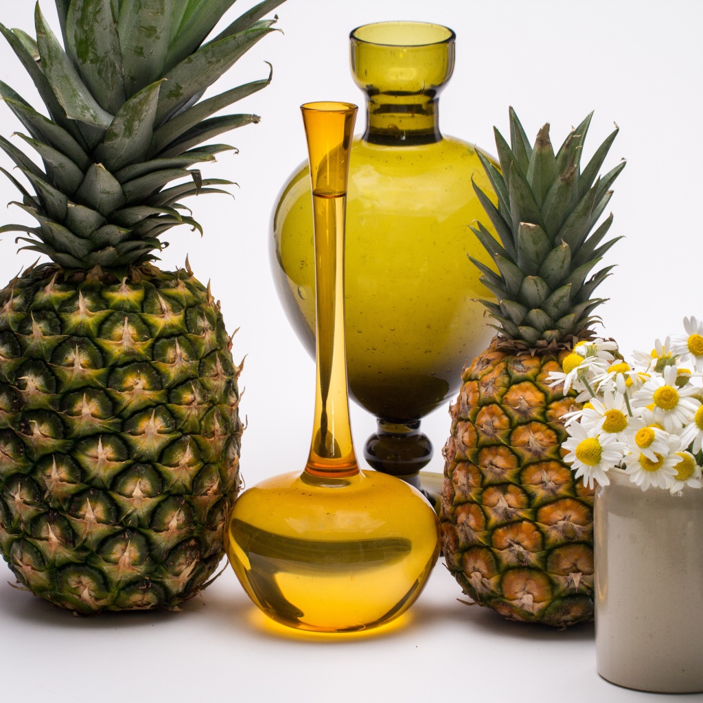 Ананасы на столе с маслом и ромашками