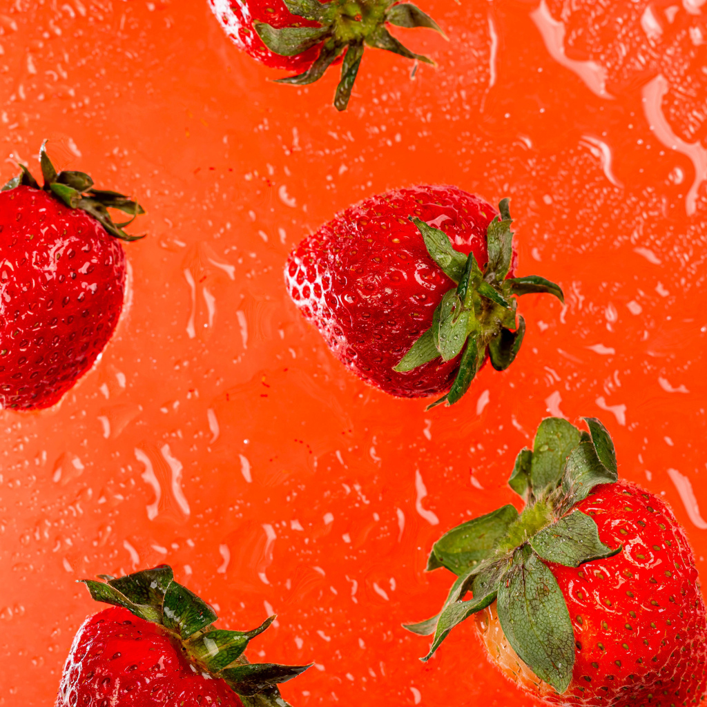 Красная клубника в воде на оранжевом фоне 