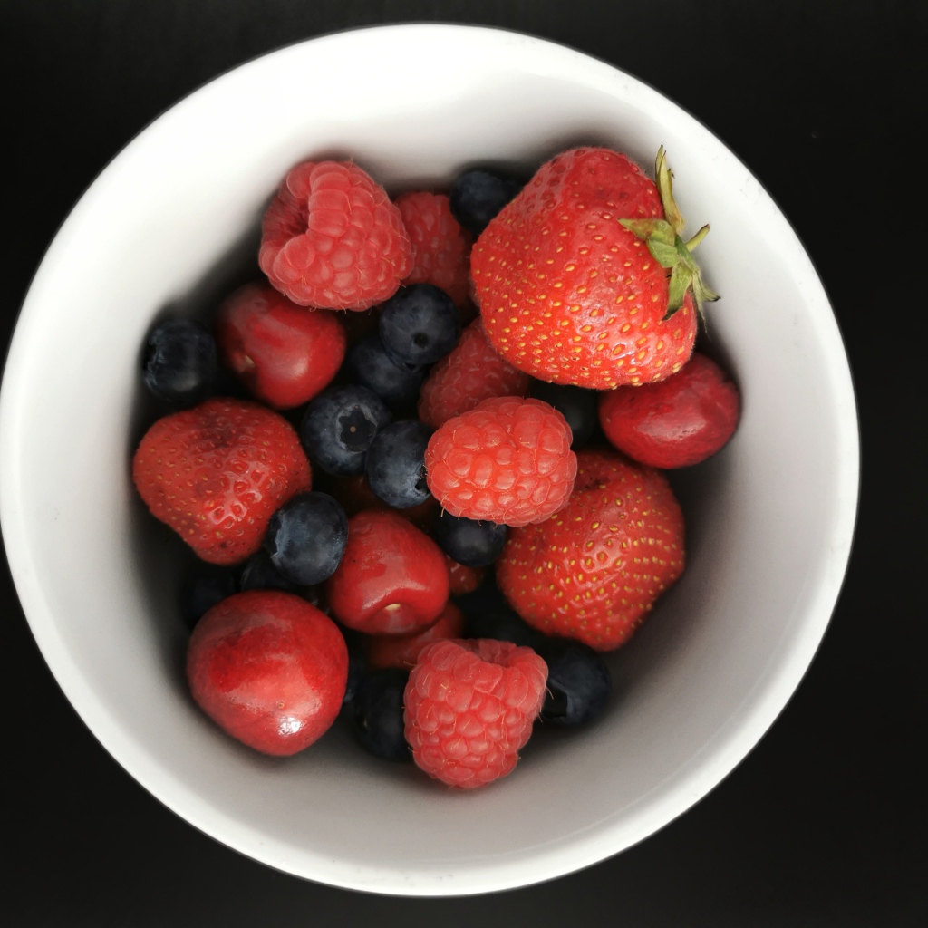 Спелые свежие ягоды в белой тарелке на белом фоне