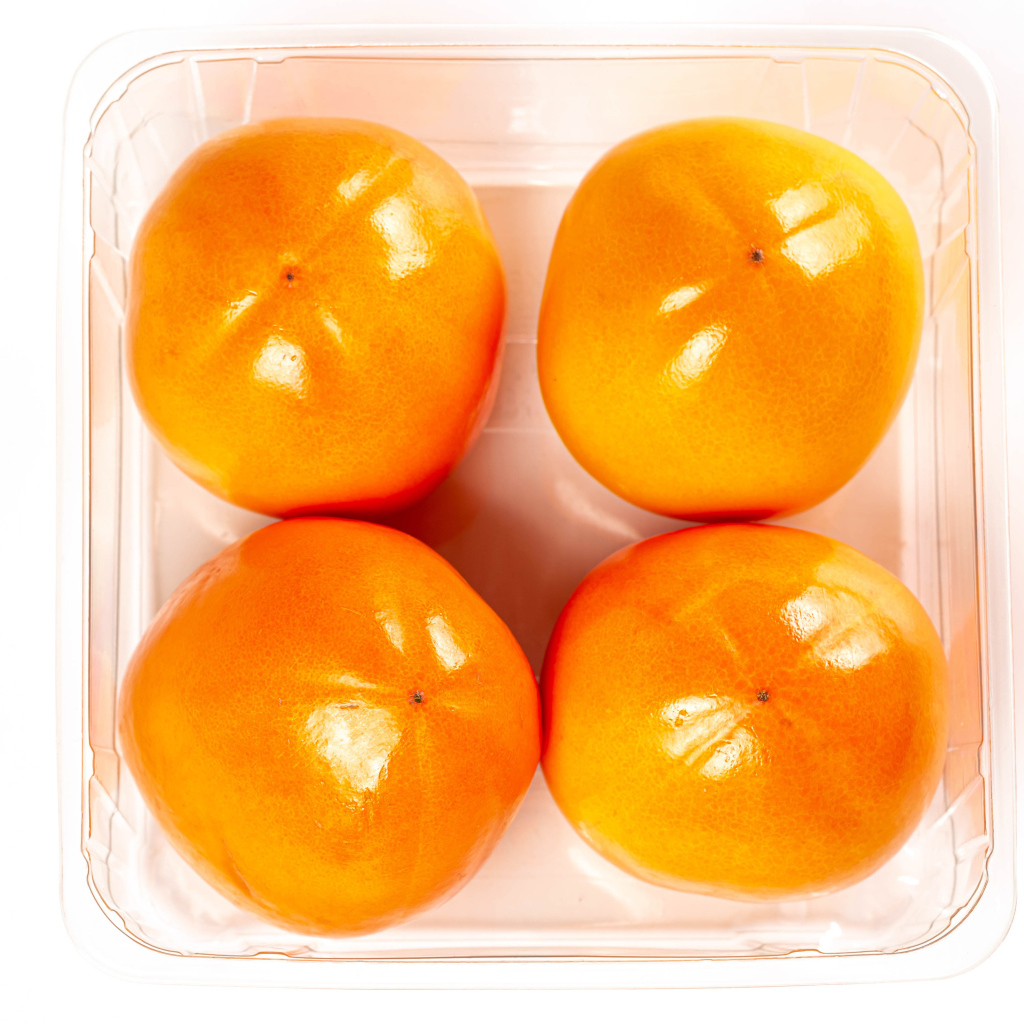 Спелая хурма с лотке на белом фоне