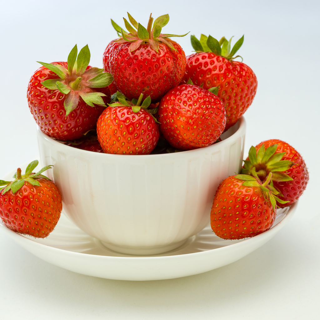 Спелая красная клубника в белой миске с блюдцем