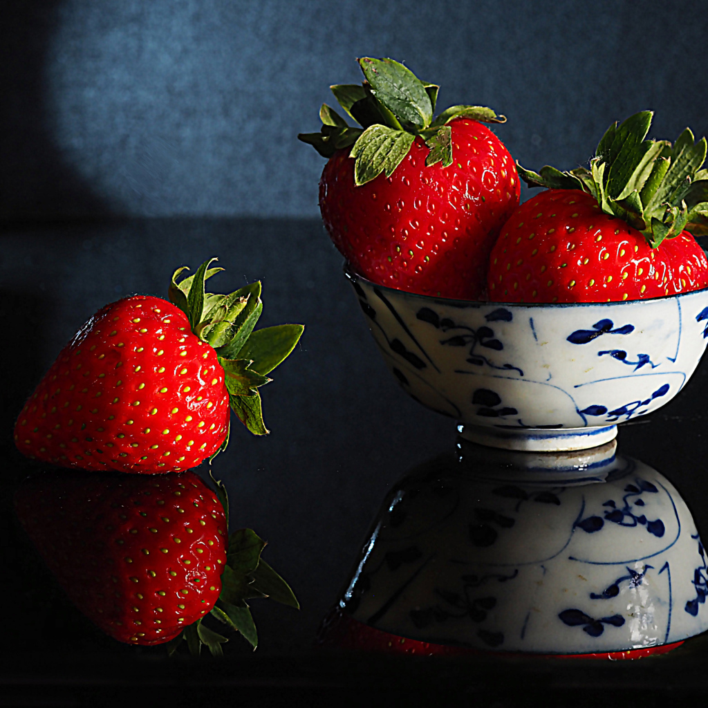 Три красные клубники в миске на столе