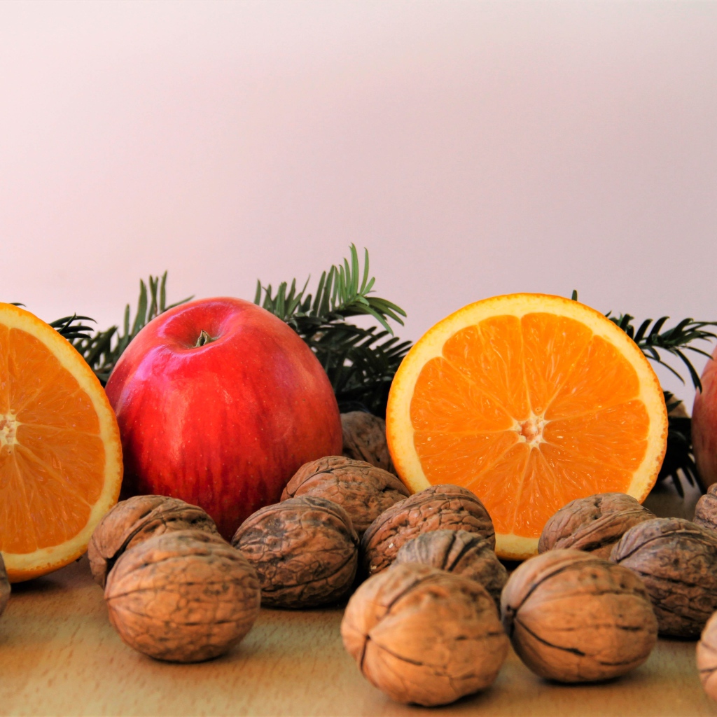 Грецкие орехи с апельсинами и яблоками на столе