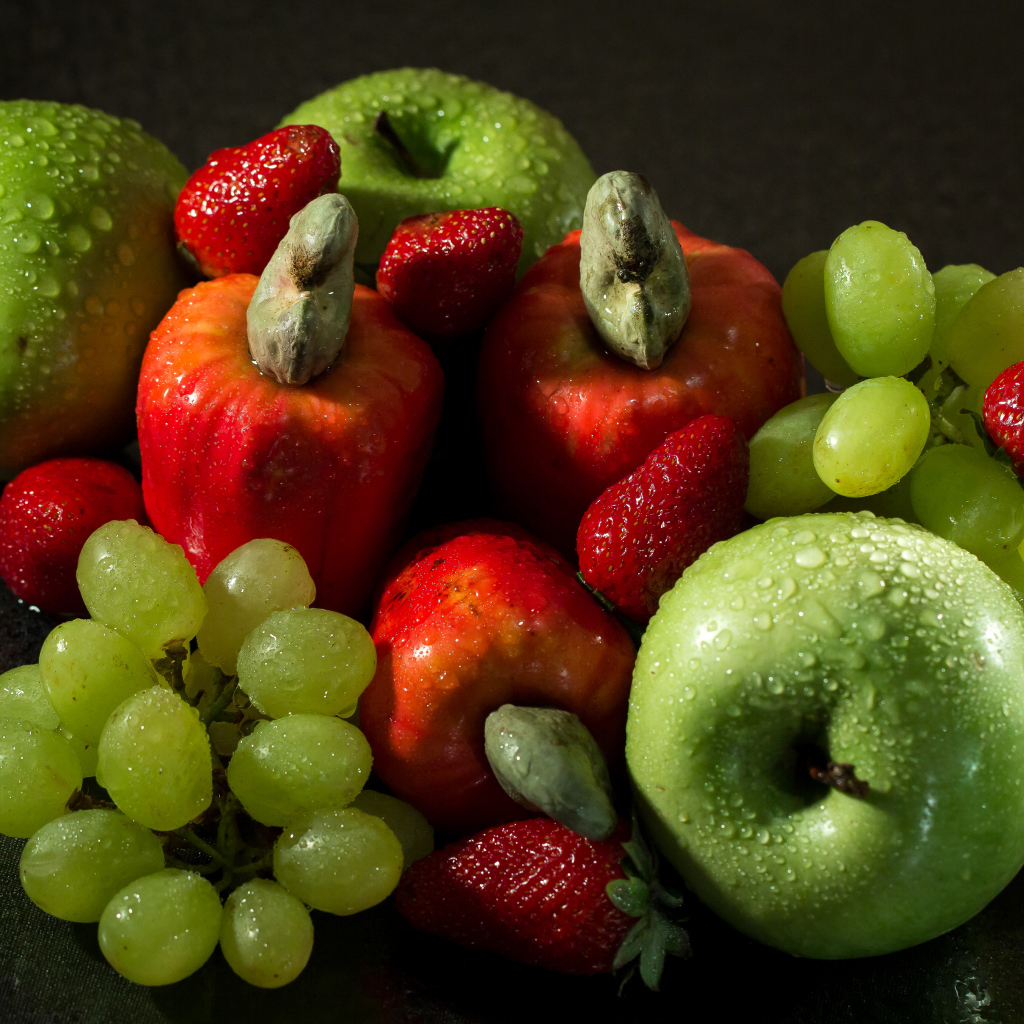 Мокрые яблоки, виноград и клубника на столе 