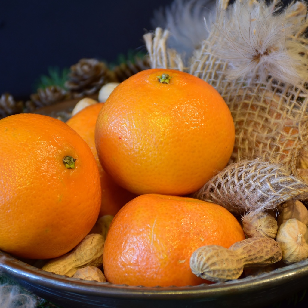 Желтые апельсины с арахисом  на тарелке