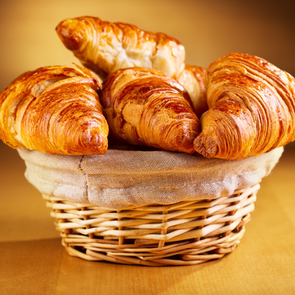 Baked ruddy croissants on the table in a basket