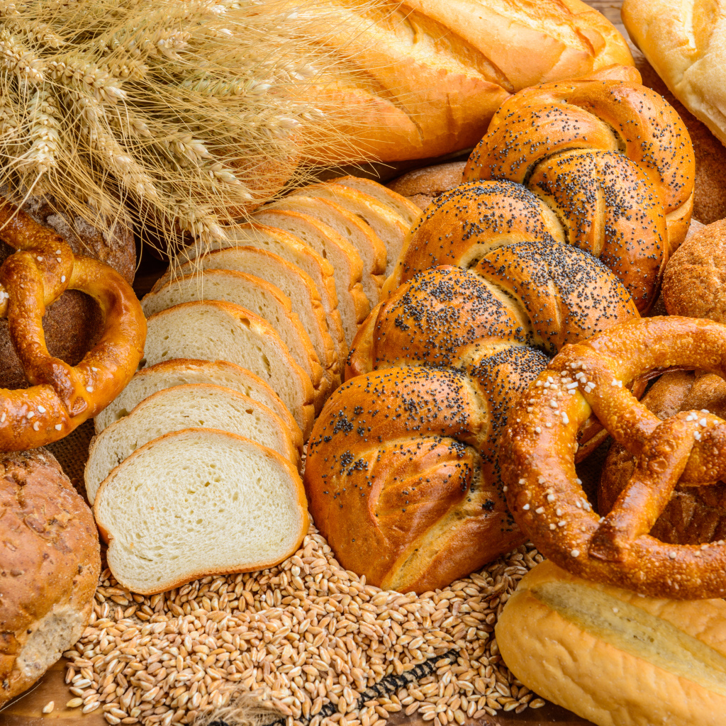 Свежая выпечка на столе с колосьями и зернами пшеницы 