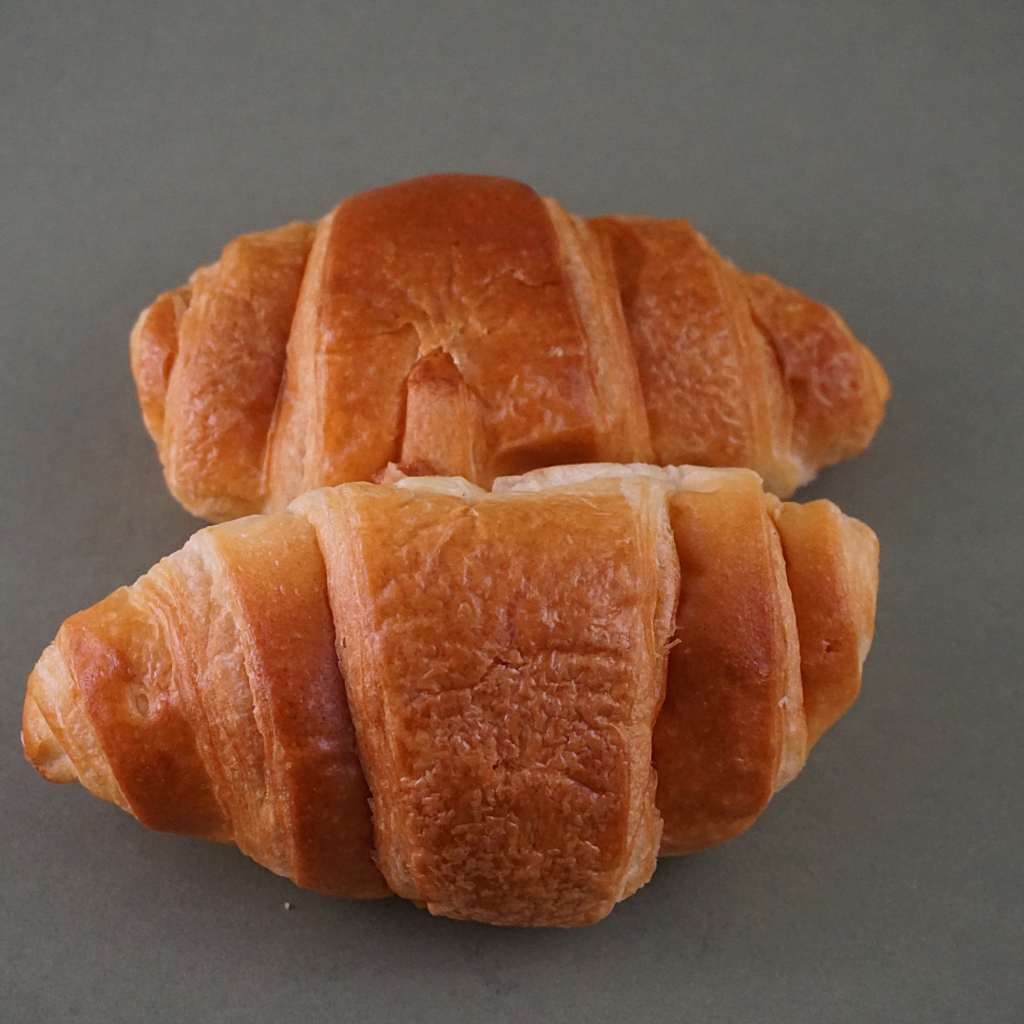 Два свежих круассана на серой поверхности