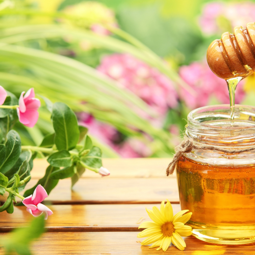 Банка ароматного меда на столе с цветами