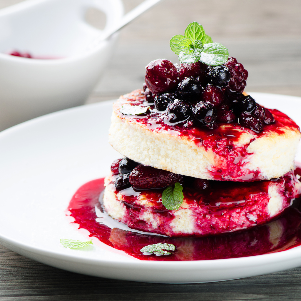 Аппетитные сырники с ягодами на белой тарелке 