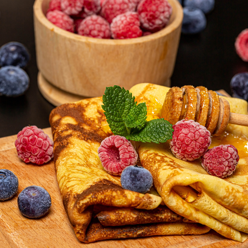 Аппетитные блины с малиной и черникой на столе