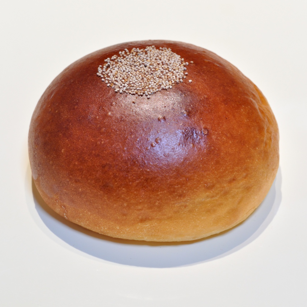 Аппетитная круглая булочка на сером фоне