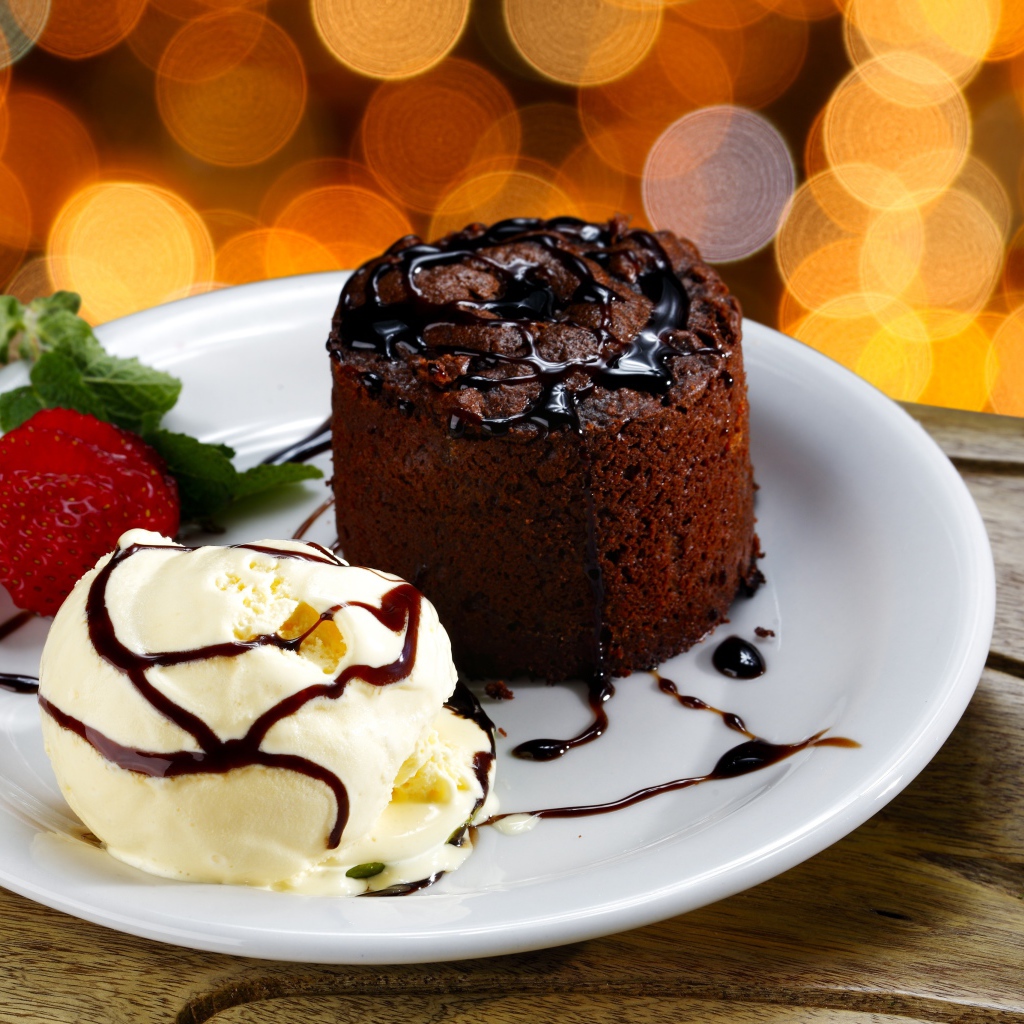 Шоколадный десерт с мороженым и клубникой на белой тарелке 