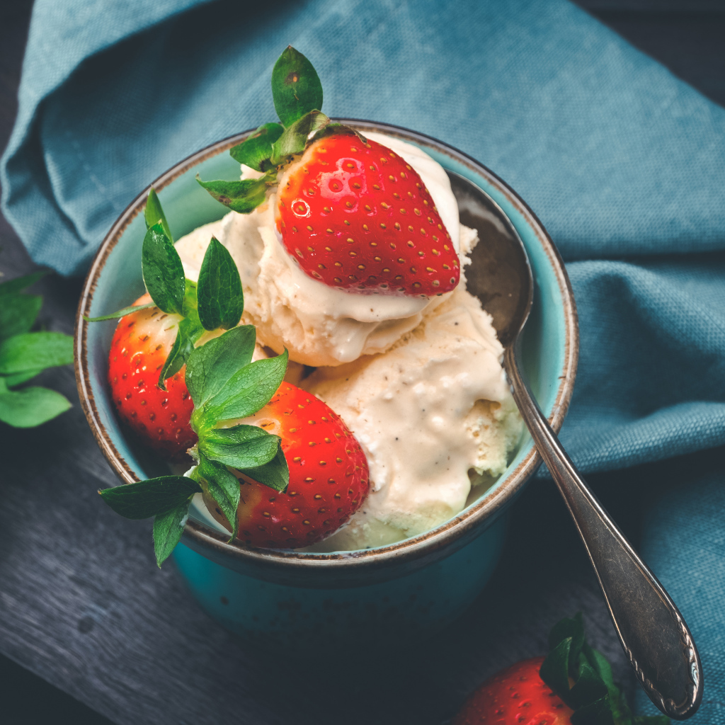 Сливочное мороженое с ягодами клубники в чашке с ложкой