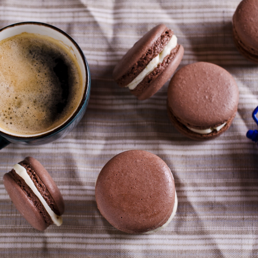 Чашка кофе на столе с десертом макарун и будильником