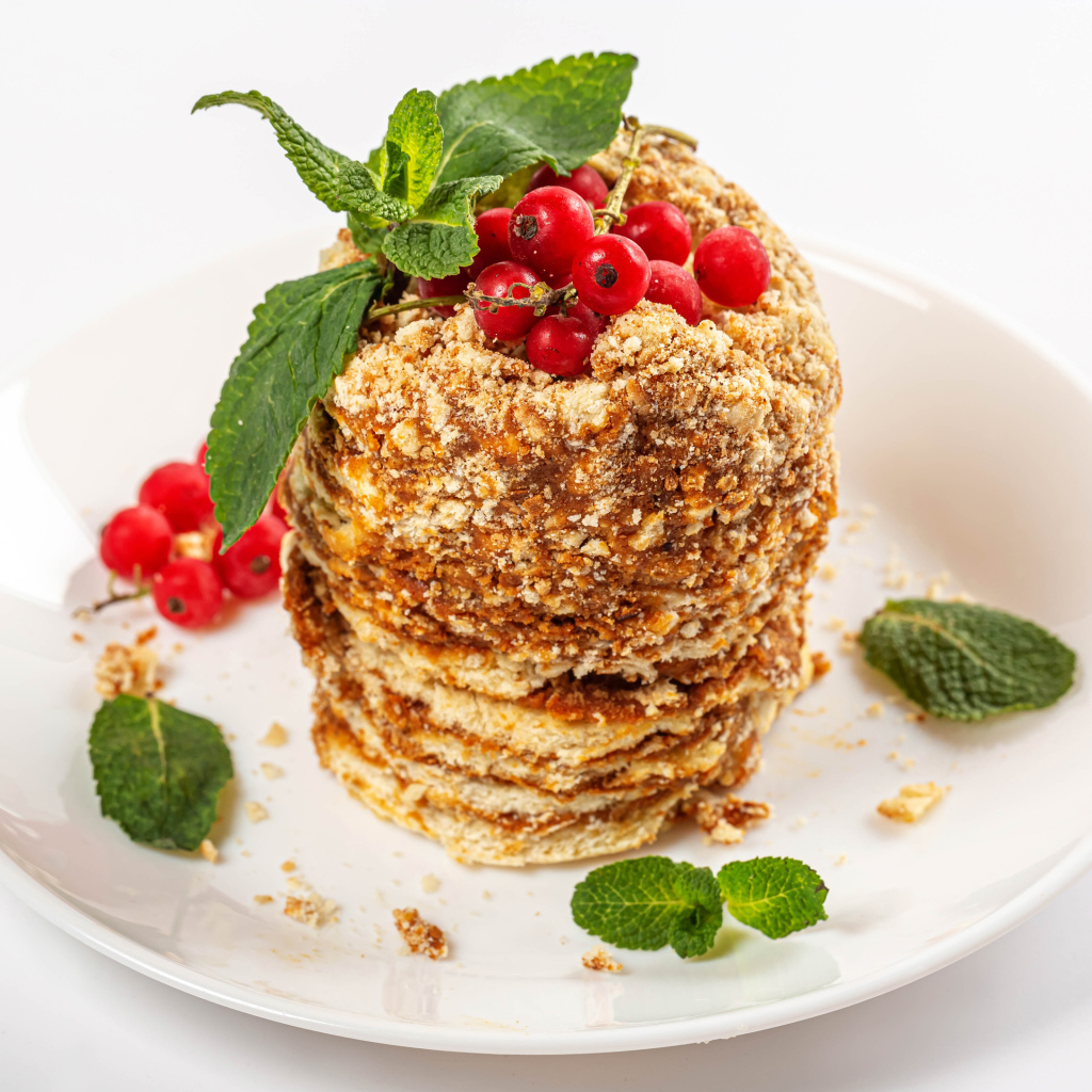 Вкусное пирожное со сгущенкой и ягодами красной смородины на белом фоне