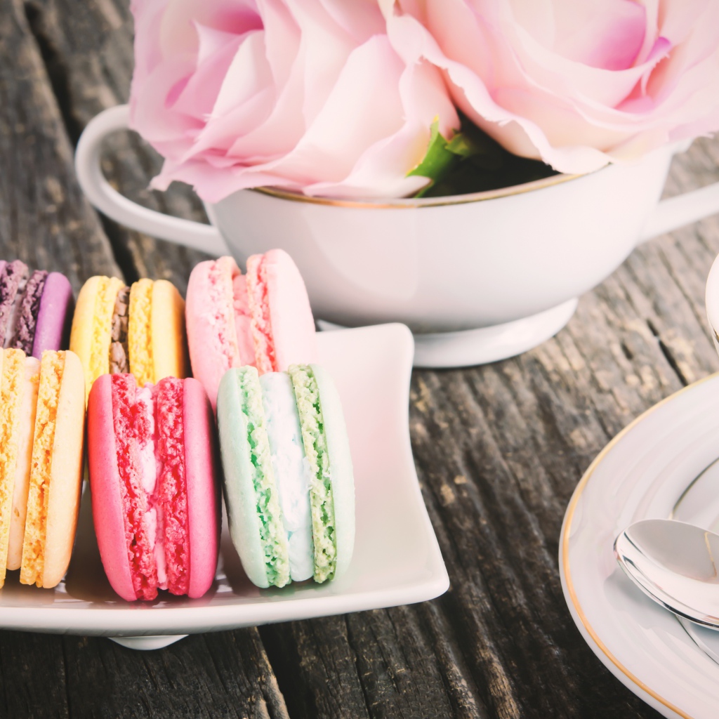 Десерт макарон на столе с чаем и цветами розы