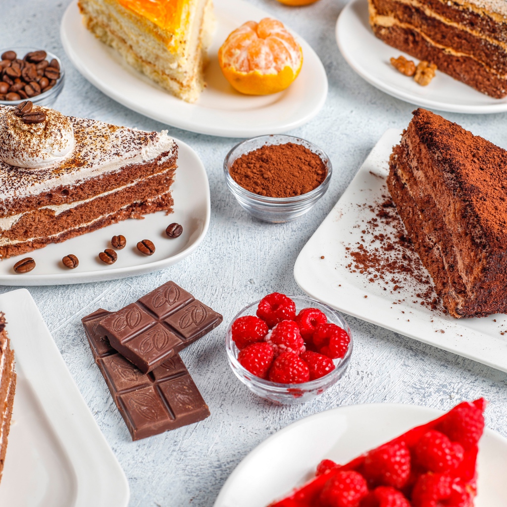 Разные куски торта на столе с малиной и шоколадом 