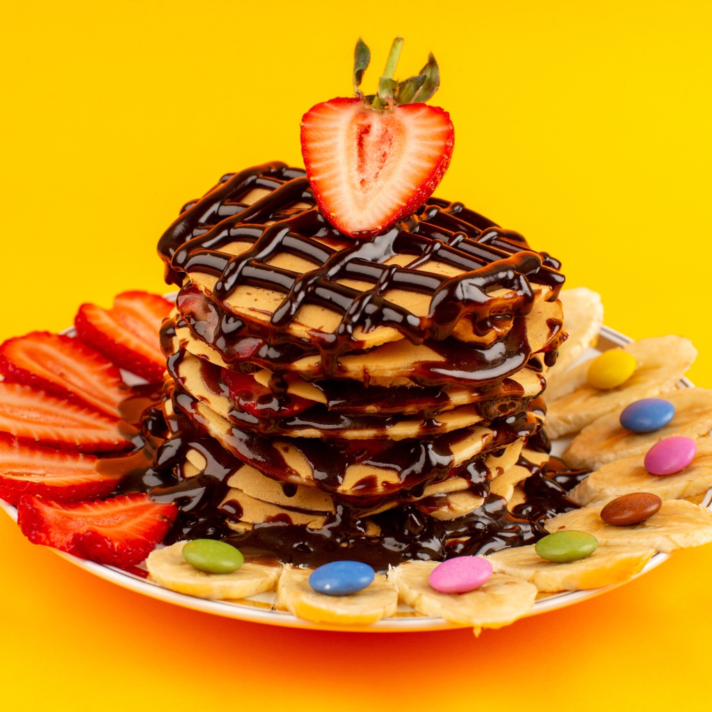 Оладьи с шоколадом, клубникой и бананом на желтом фоне 