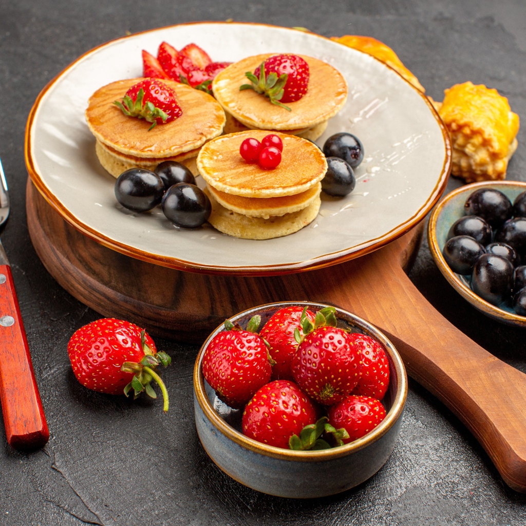 Оладьи с виноградом и клубникой на тарелке 