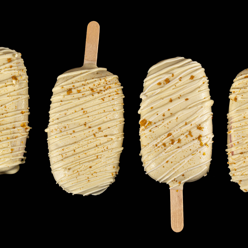 Мороженое на палочке в белом шоколаде на черном фоне