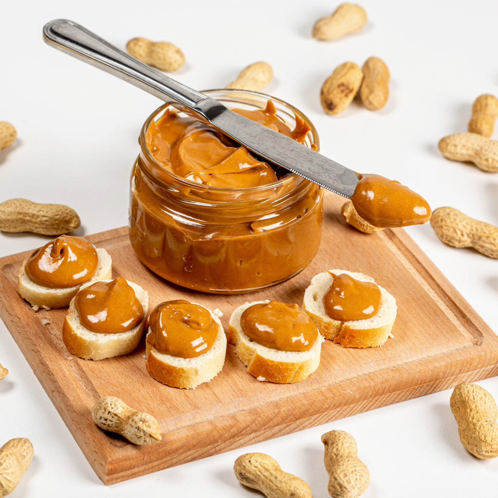 Ореховая паста на столе с батоном и арахисом