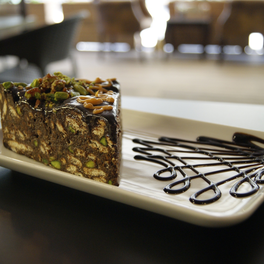 Кусок торта с фисташками на белой тарелке 