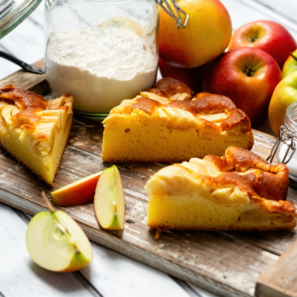 Куски пирога на столе с яблоками и мукой