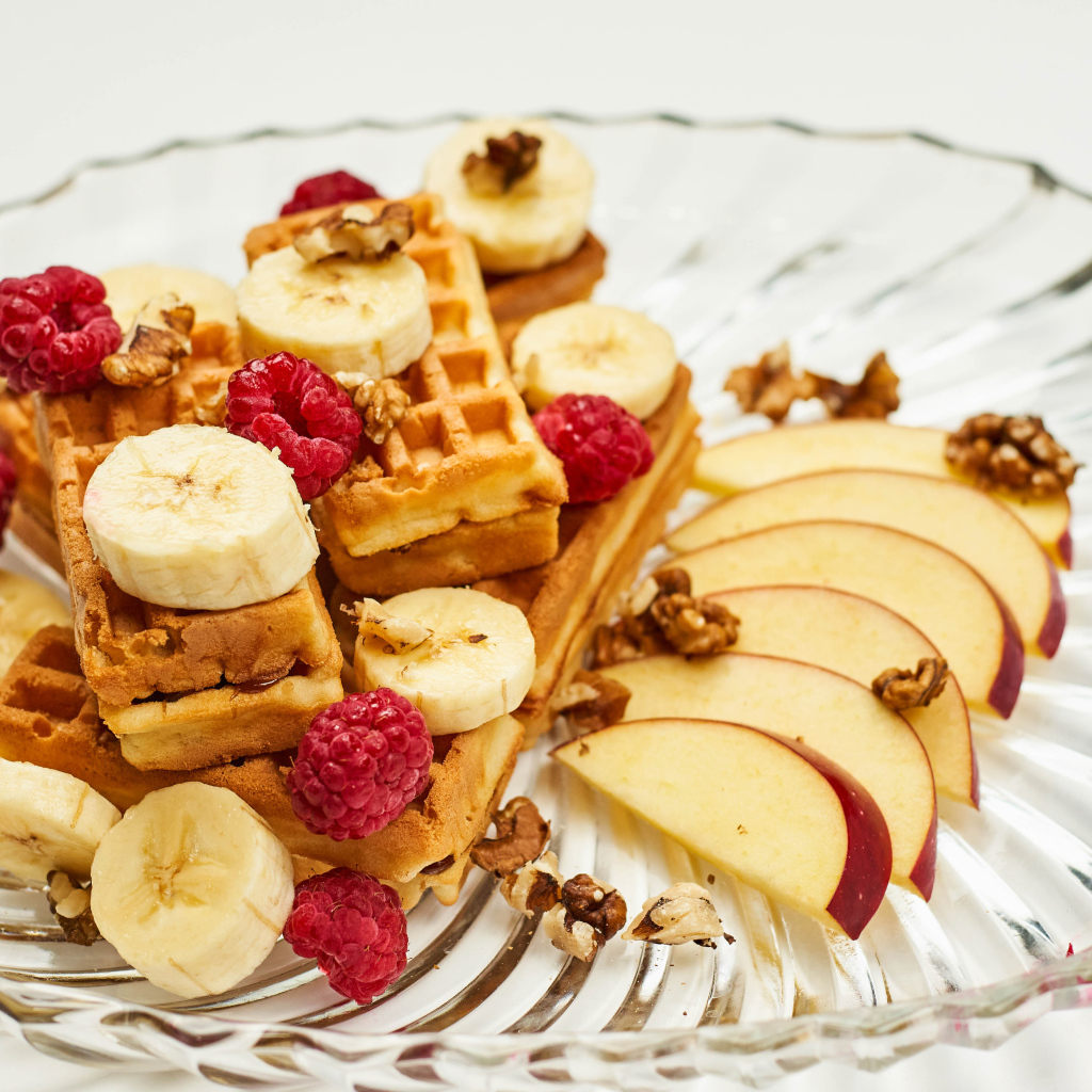Сладкие вафли на тарелке с бананом, малиной и яблоком