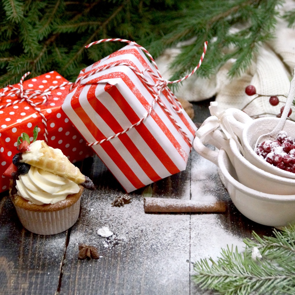 Два подарка на столе с еловой веткой и кексами 