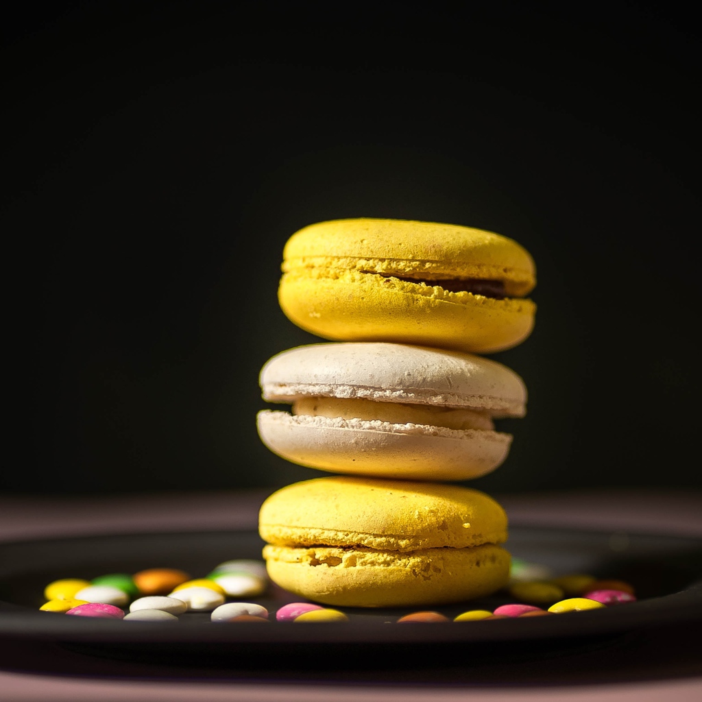 Желтый десерт макарун на тарелке