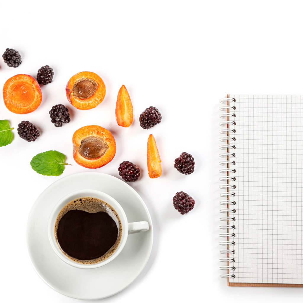 Чашка кофе, тетрадь, черника и абрикос на белом фоне