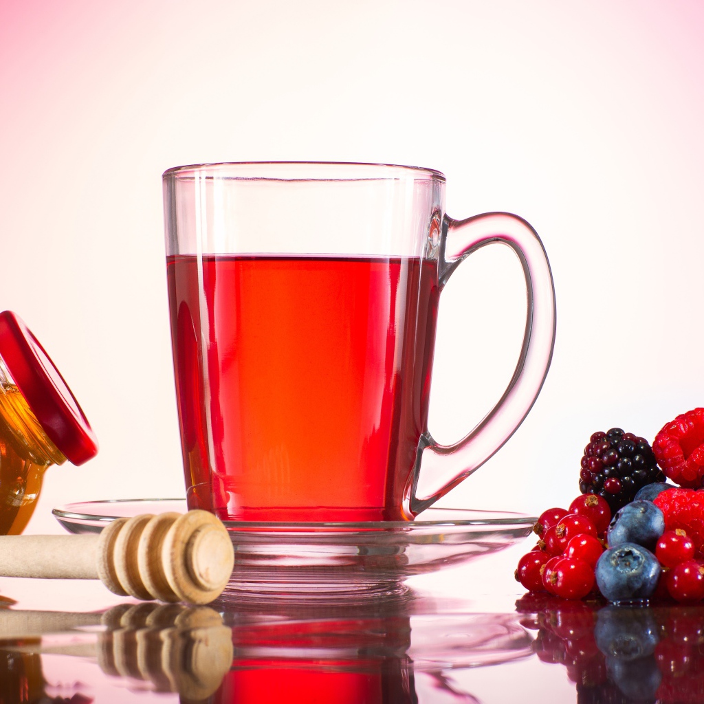 Чашка чая с медом на столе с ягодами