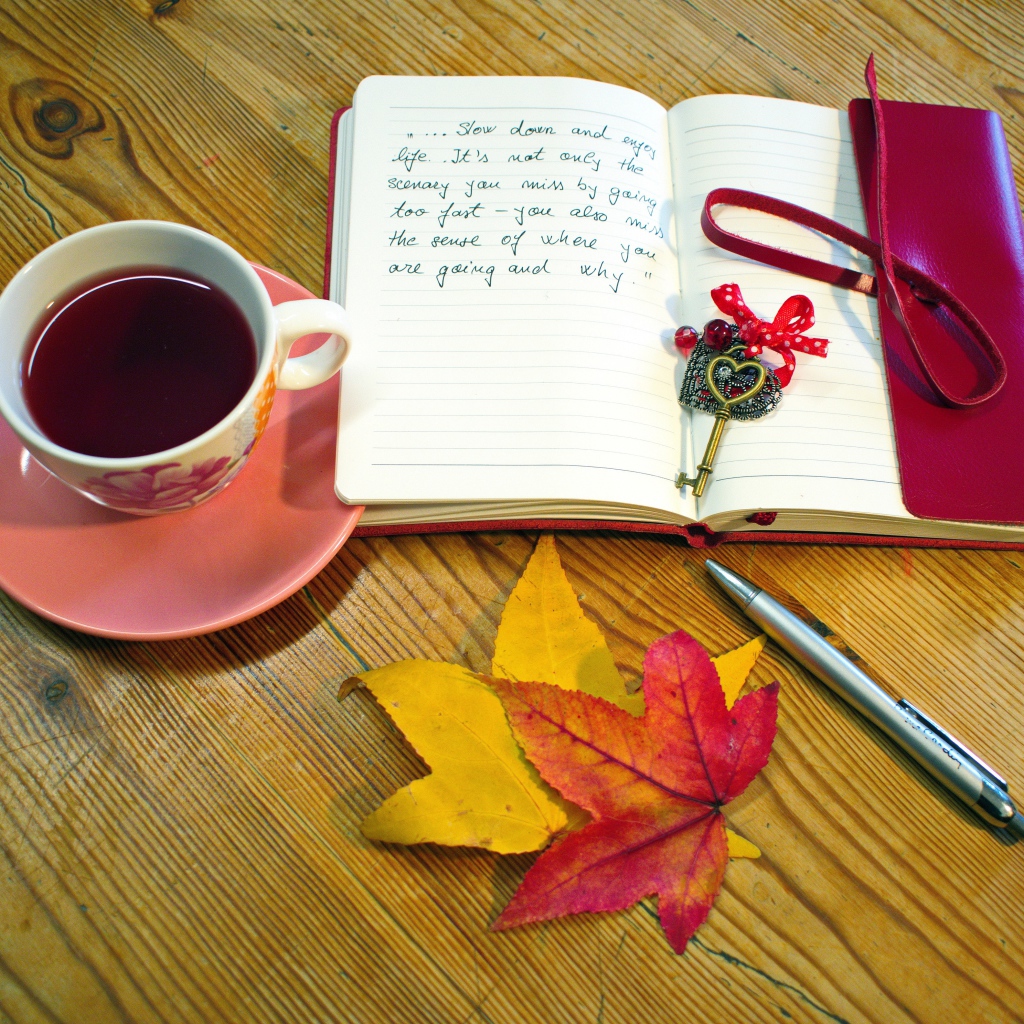 Чашка чая с блокнотом и листьями на столе 