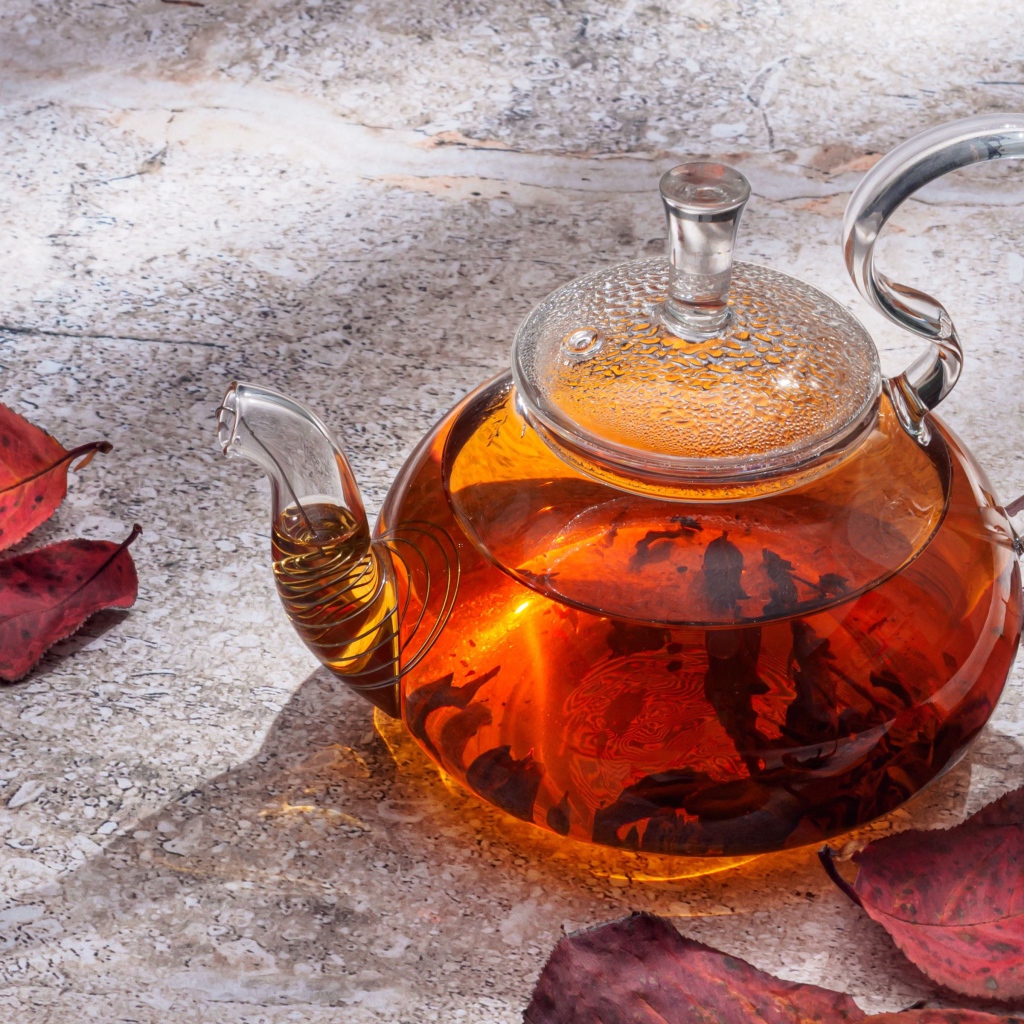Стеклянный чайник на столе с листьями
