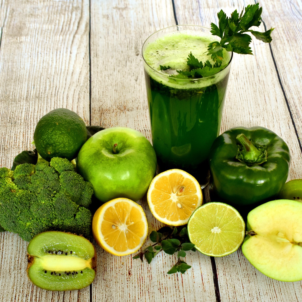 Зеленый свежий смузи на столе с овощами и фруктами 
