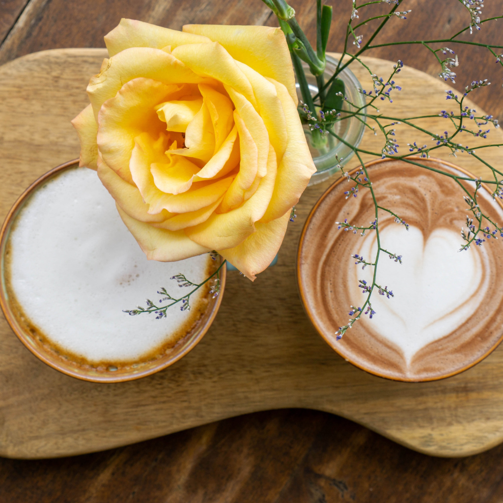 Две чашки капучино на столе с розой