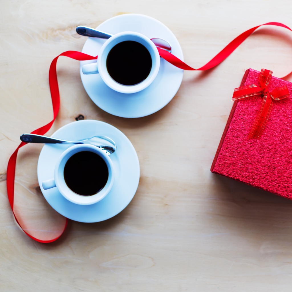 Две чашки кофе на столе с подарком