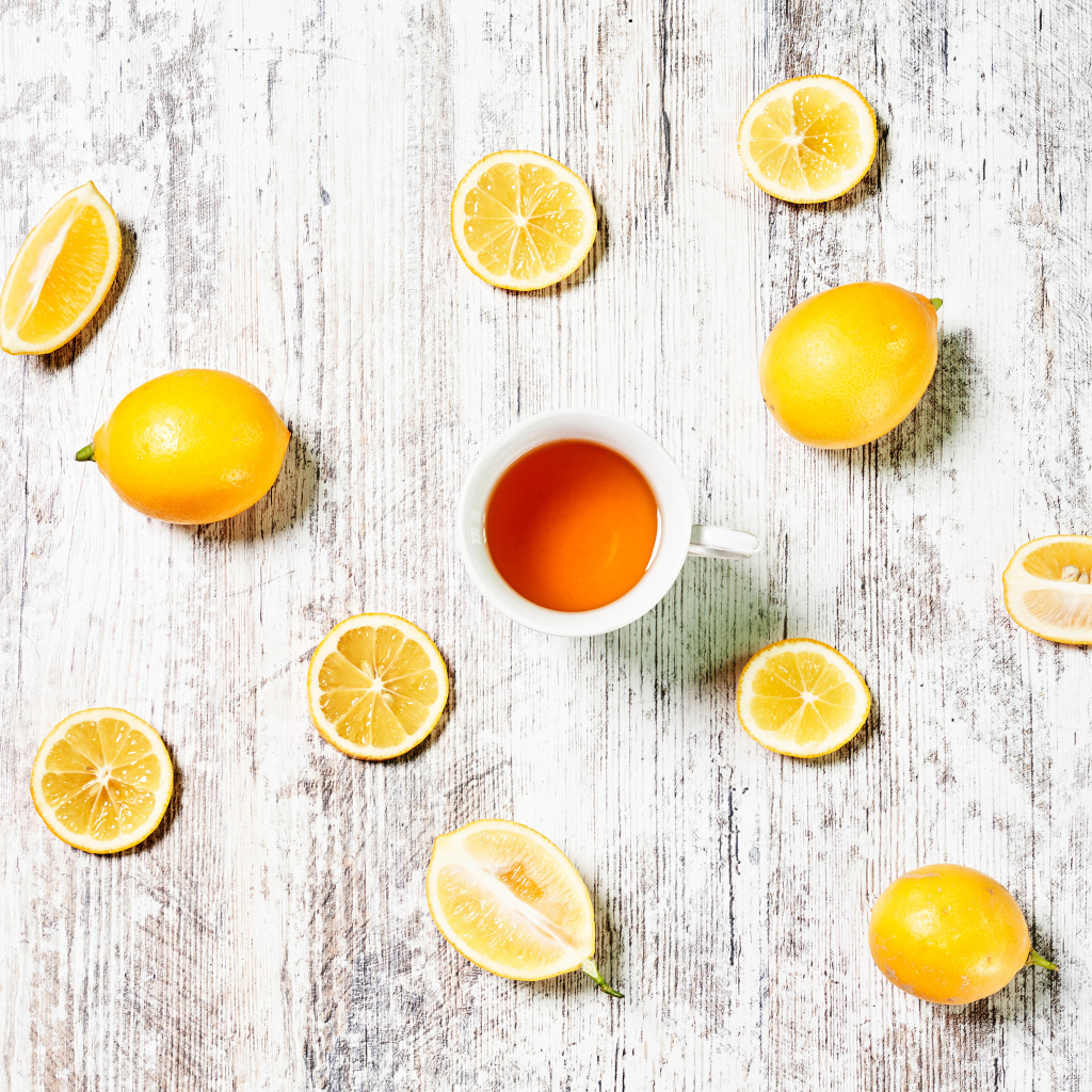 Желтые лимоны с чаем на белом столе 