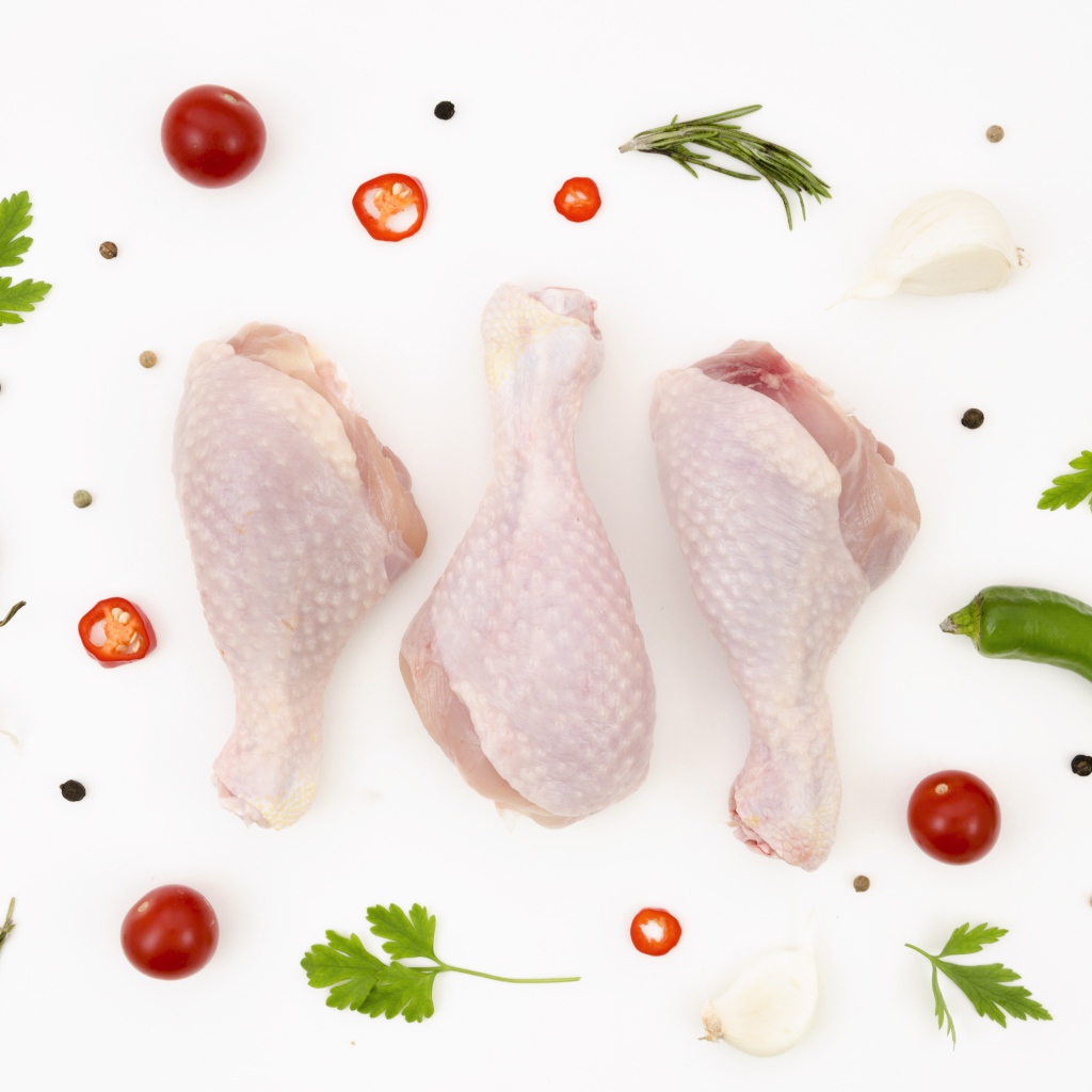 Свежие куриные бедра с перцем и помидорами на белом фоне 