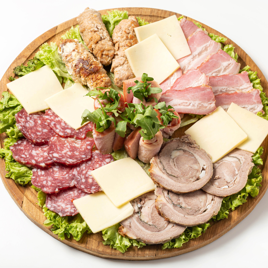 Мясные продукты с сыром на доске на белом фоне