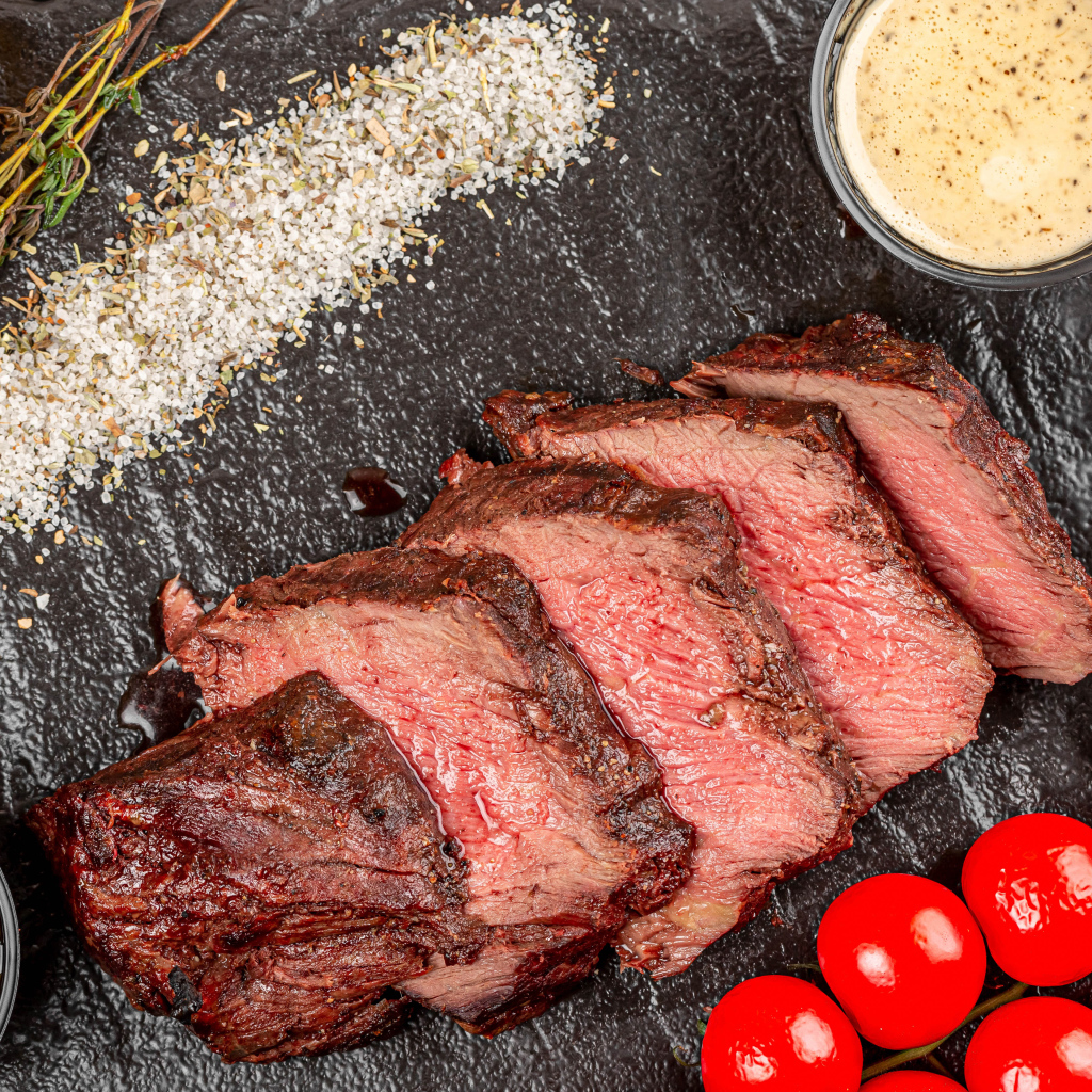 Мясо с помидорами и соусами на доске 