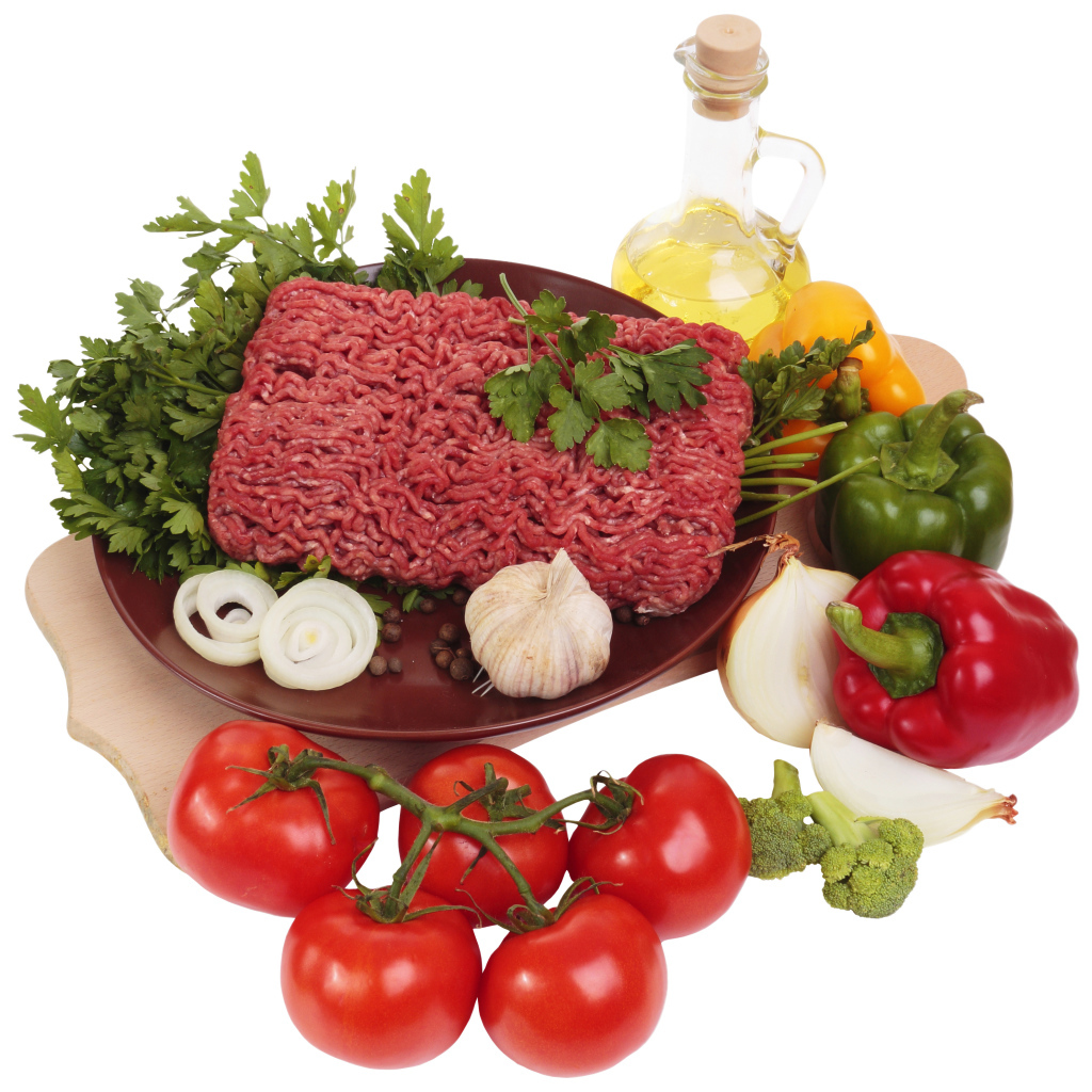 Minced meat on a white plate with vegetables and herbs