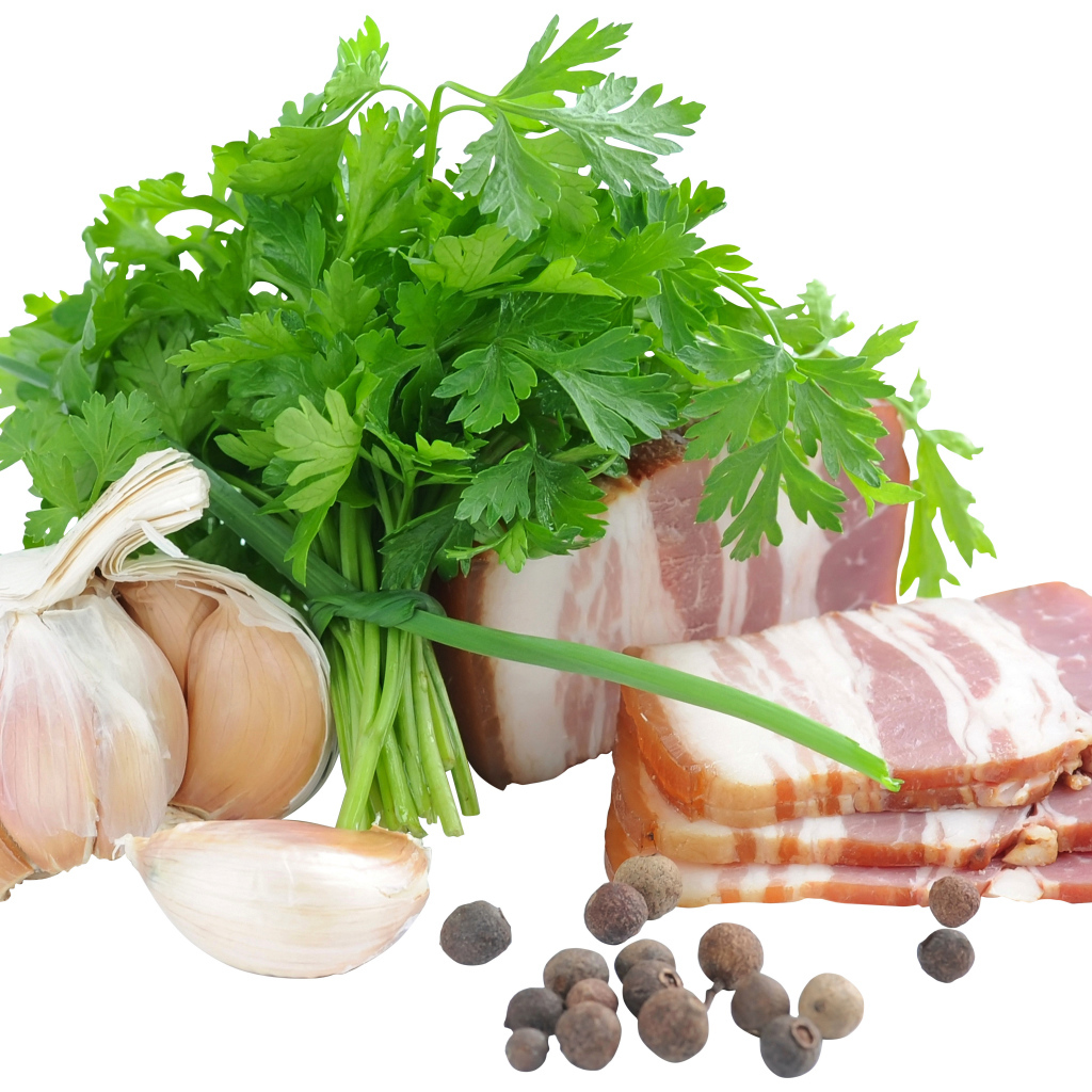 Кусок сала на белом фоне с зеленью петрушки и специями