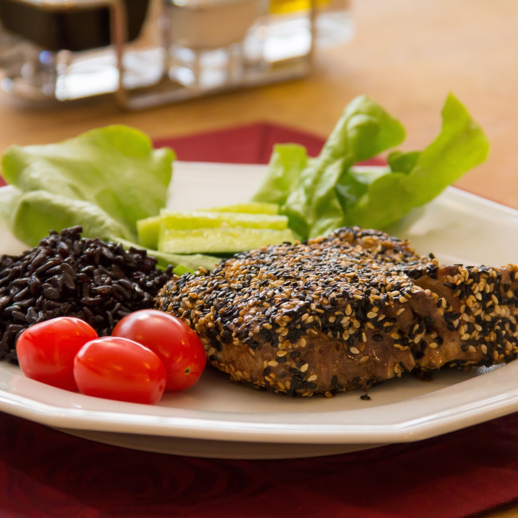 Кусок мяса на тарелке с рисом и овощами 