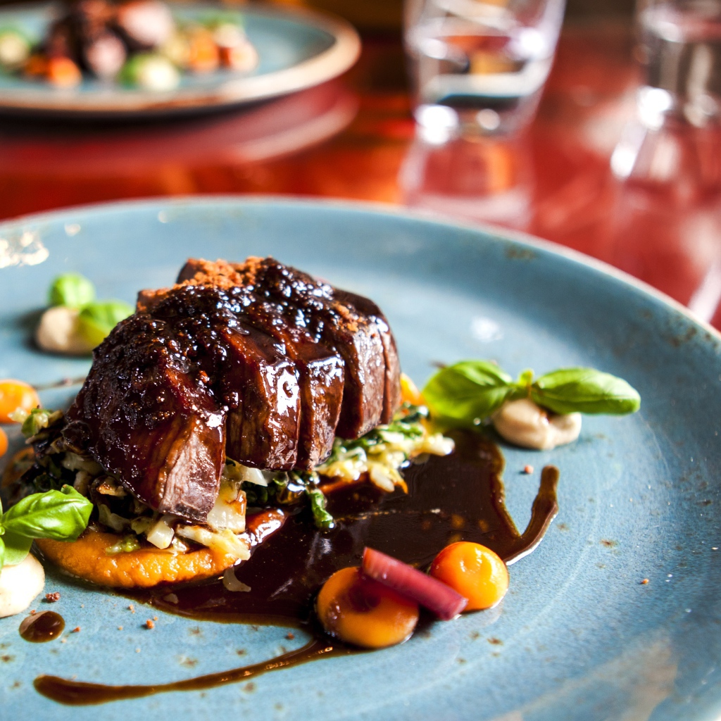 Кусок мяса с соусом на тарелке в ресторане