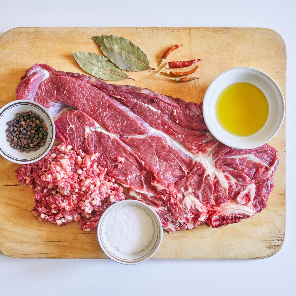 Кусок мяса со специями и оливковым маслом на доске 