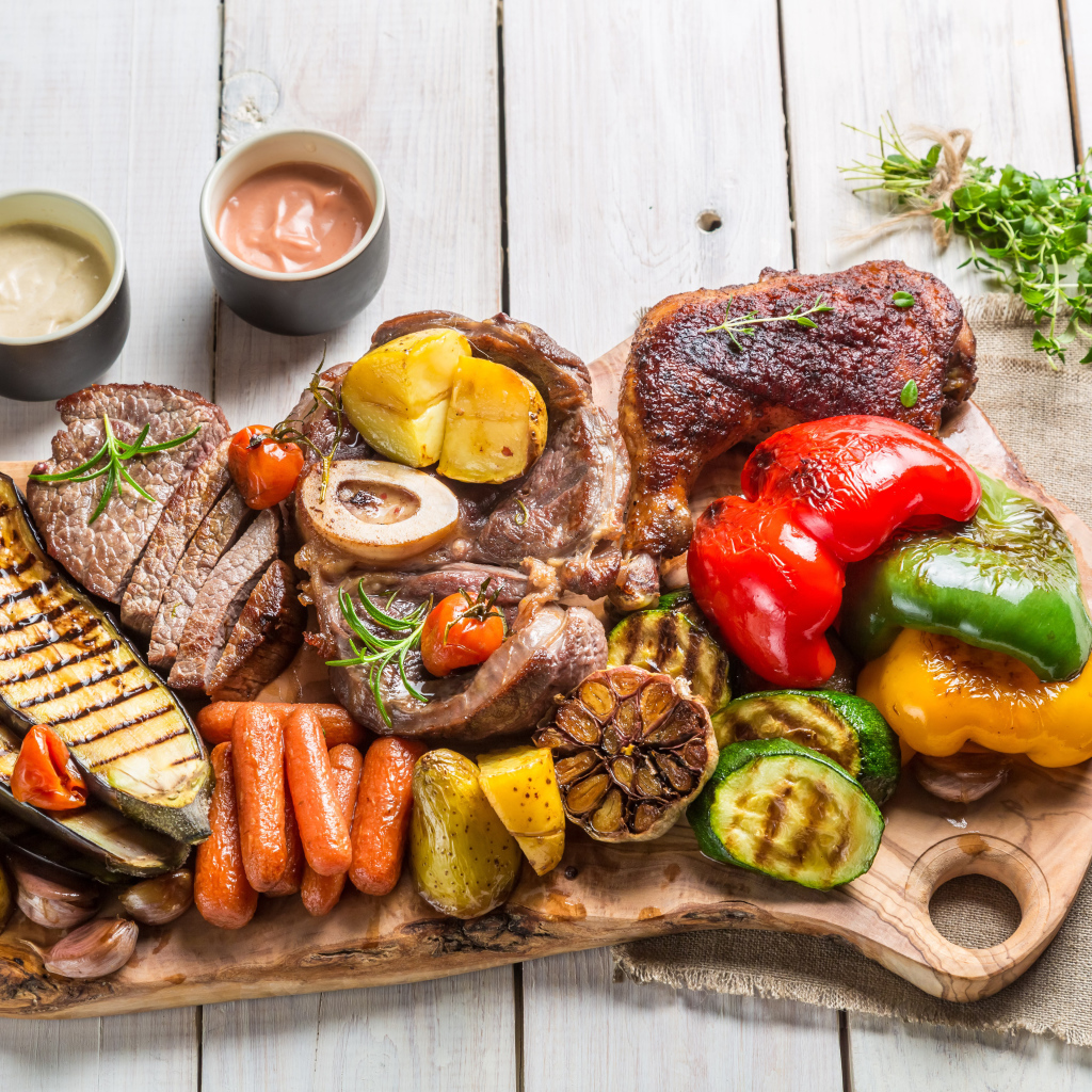 Pieces of baked meat on a board with vegetables