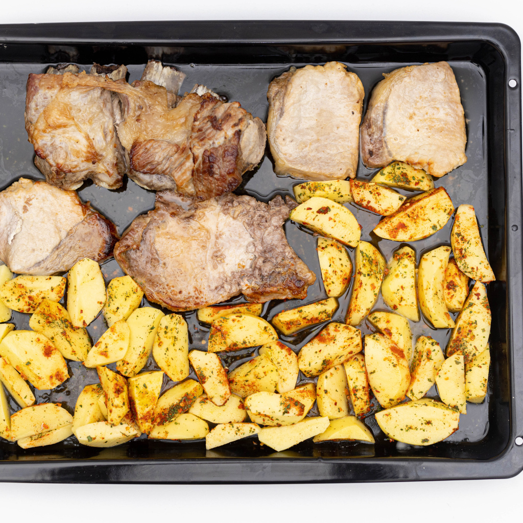 Свинина на противне с картофелем на белом фоне 