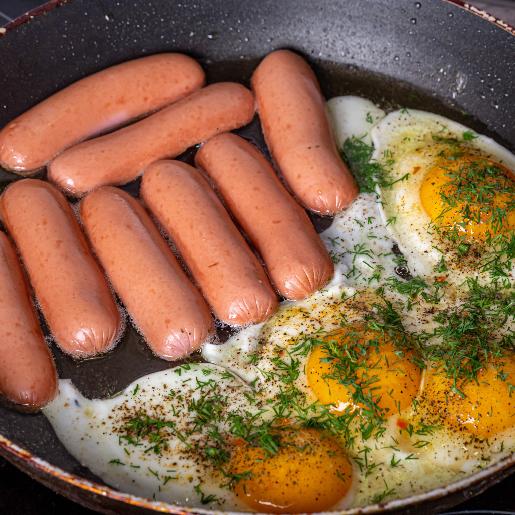 Сосиски с яичницей на сковороде